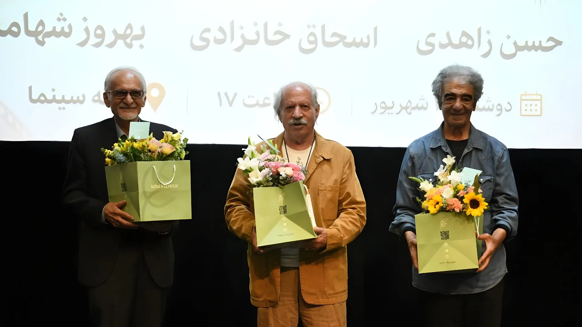 سه مرد میانسال با بسته‌های گل در مراسم سینمایی