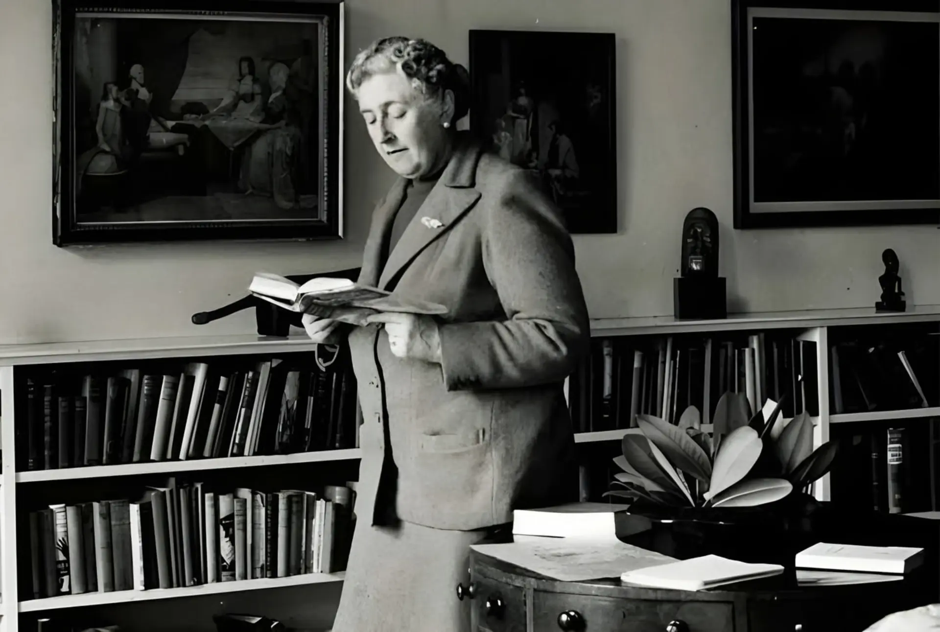 آگاتا کریستی (Agatha Christie) کتابی را در کتابخانه‌ی شخصی خود مطالعه می‌کند