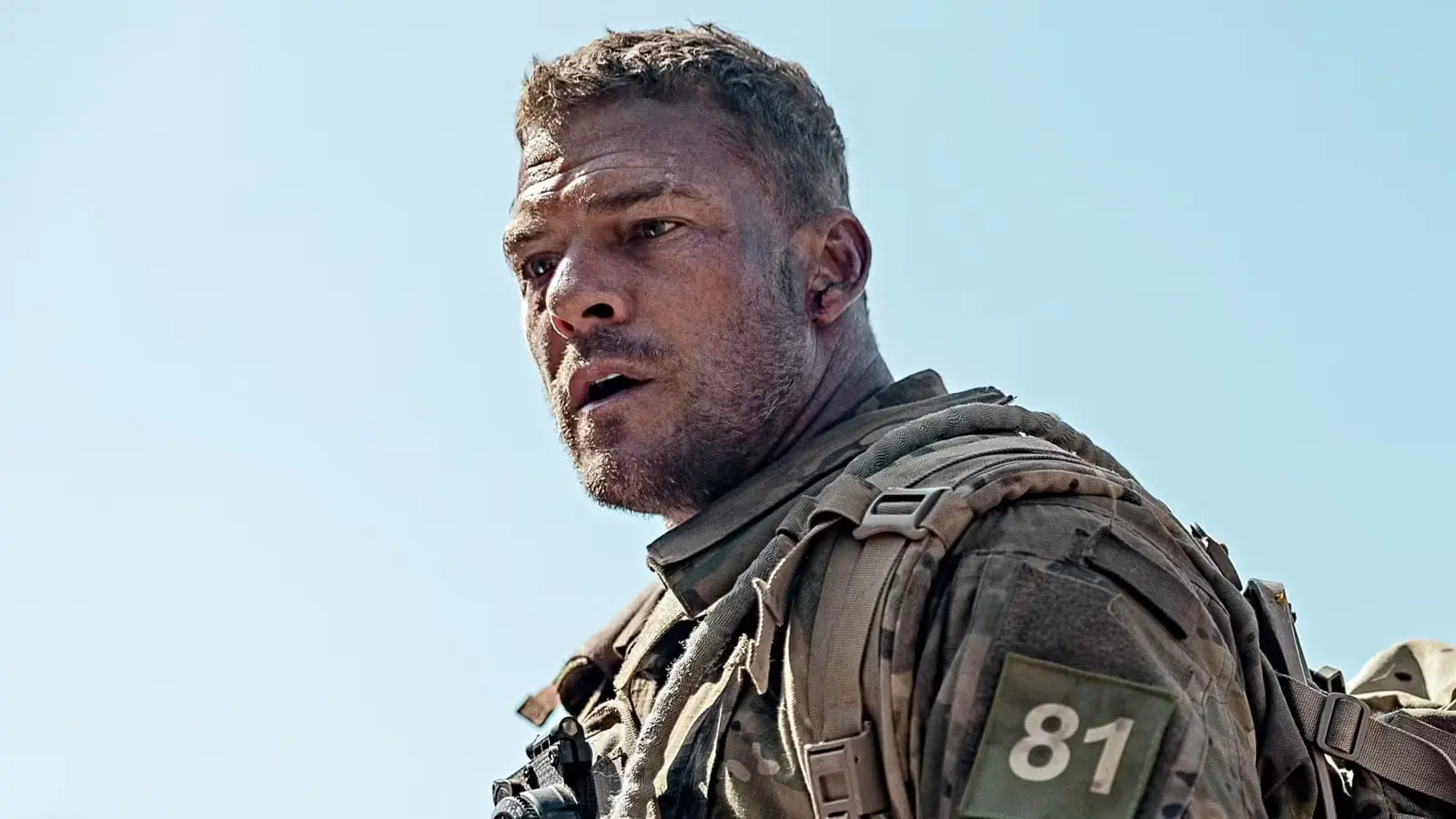 آلن ریچسون (Alan Ritchson) با لباس نظامی و تجهیزات جنگی در فضای باز