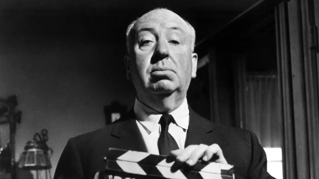 آلفرد هیچکاک (Alfred Hitchcock) در حال نگه داشتن یک کلپر سینمایی