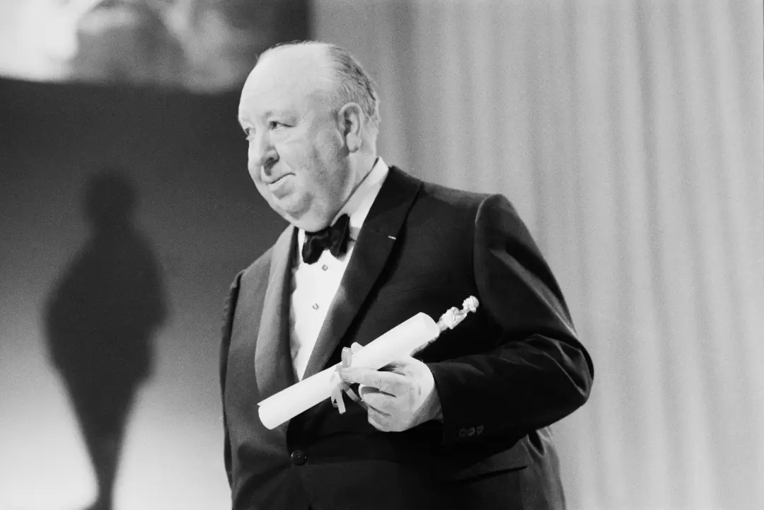 آلفرد هیچکاک (Alfred Hitchcock) در مراسم اهدای جایزه با یک مدرک رولی در دست