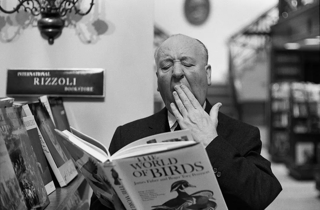 آلفرد هیچکاک (Alfred Hitchcock) در حال خمیازه کشیدن هنگام مطالعه کتاب