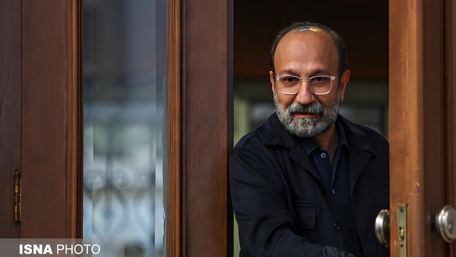 اصغر فرهادی (Asghar Farhadi) با عینک در قاب یک در چوبی