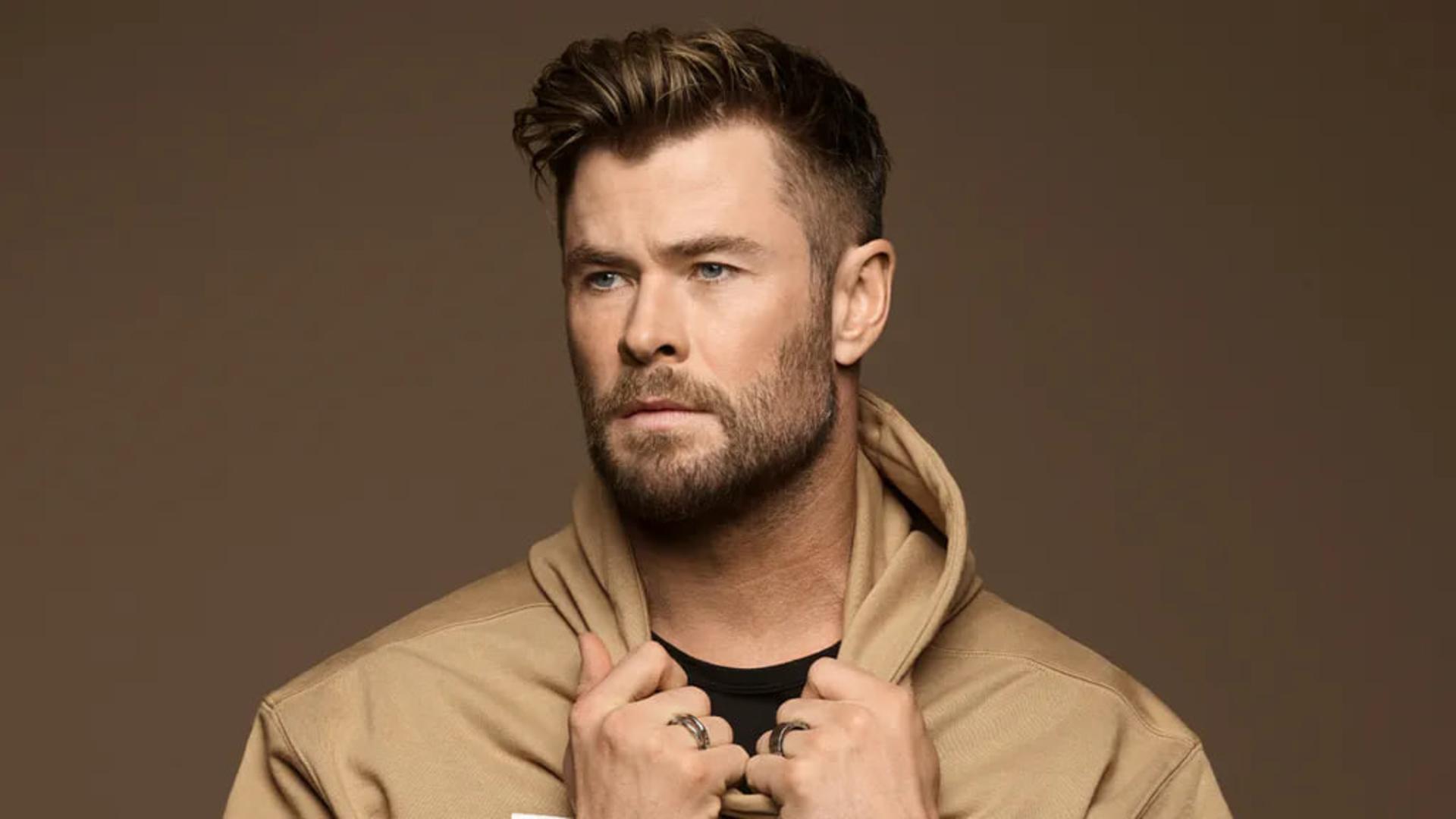 کریس همسورث (Chris Hemsworth) با نگاهی به دوردست در مقابل پس‌زمینه قهوه‌ای