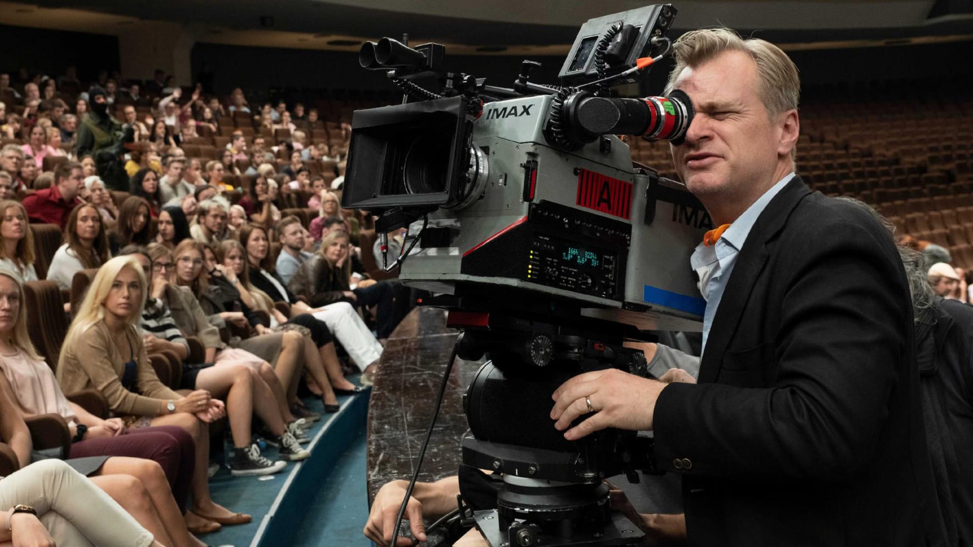 کریستوفر نولان (Christopher Nolan) در حال کار با دوربین سینمایی آی‌مکس (IMAX) در یک سالن سینما