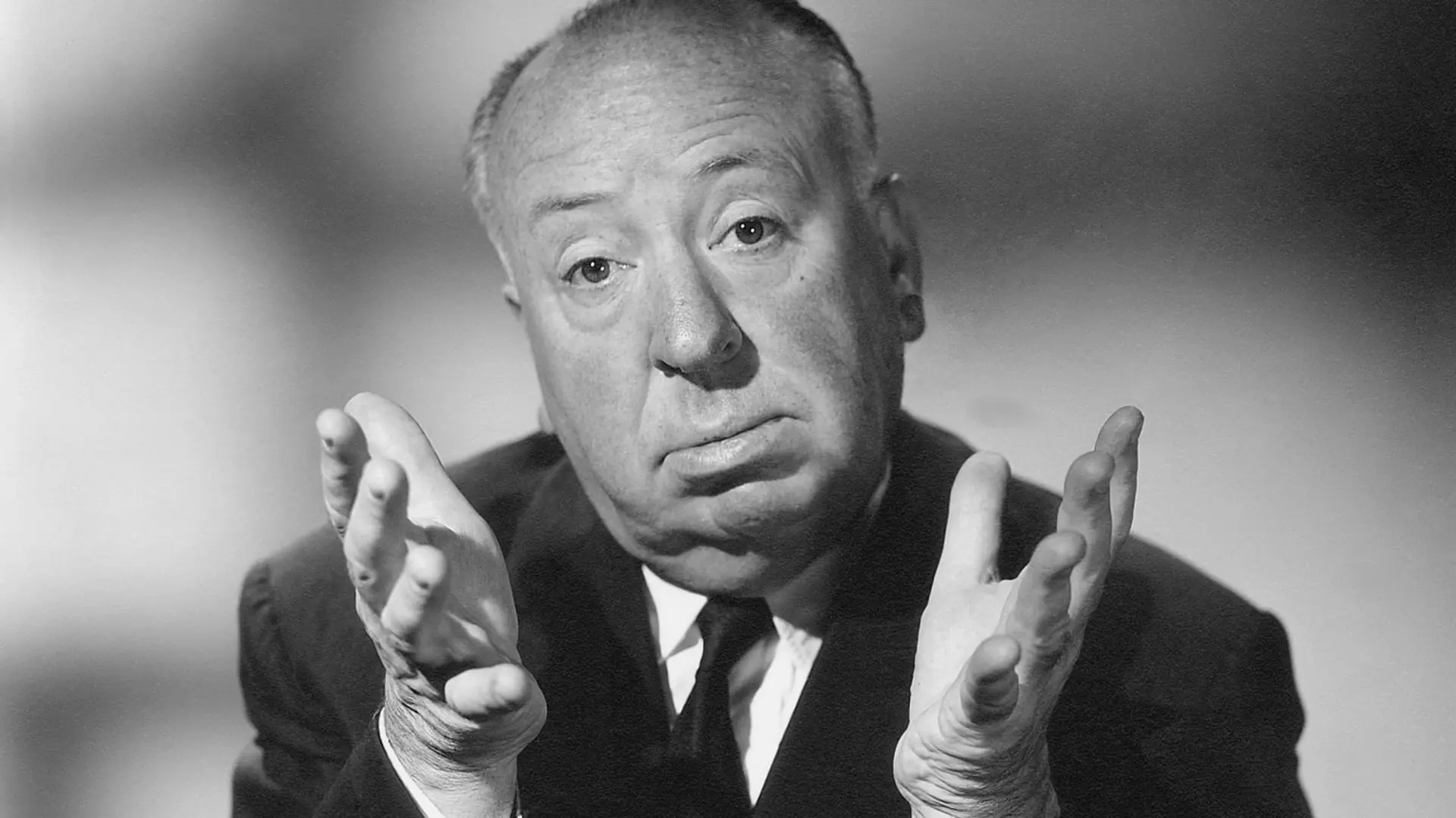 چهره آلفرد هیچکاک (Alfred Hitchcock) با دست‌های باز در مقابل پس‌زمینه روشن