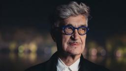ویم وندرس (Wim Wenders) با عینک با فریم آبی در فضای باز