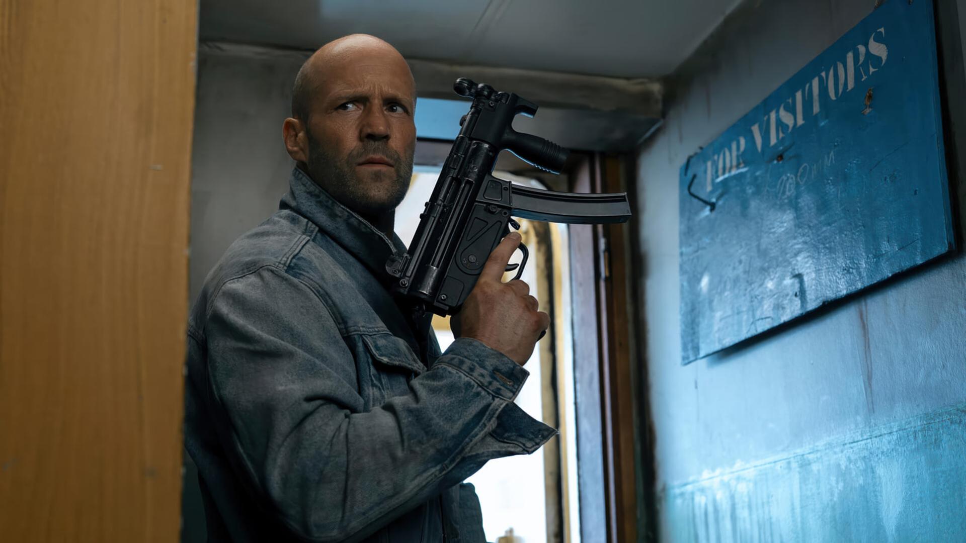 جیسون استاتهام (Jason Statham) در حال نگه داشتن یک مسلسل در محیطی بسته