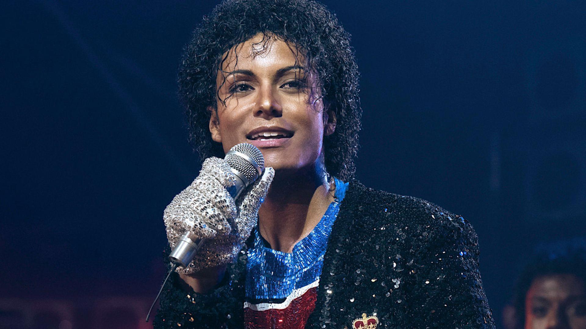 بازیگر نقش مایکل جکسون (Michael Jackson) در حال آواز خواندن با میکروفون