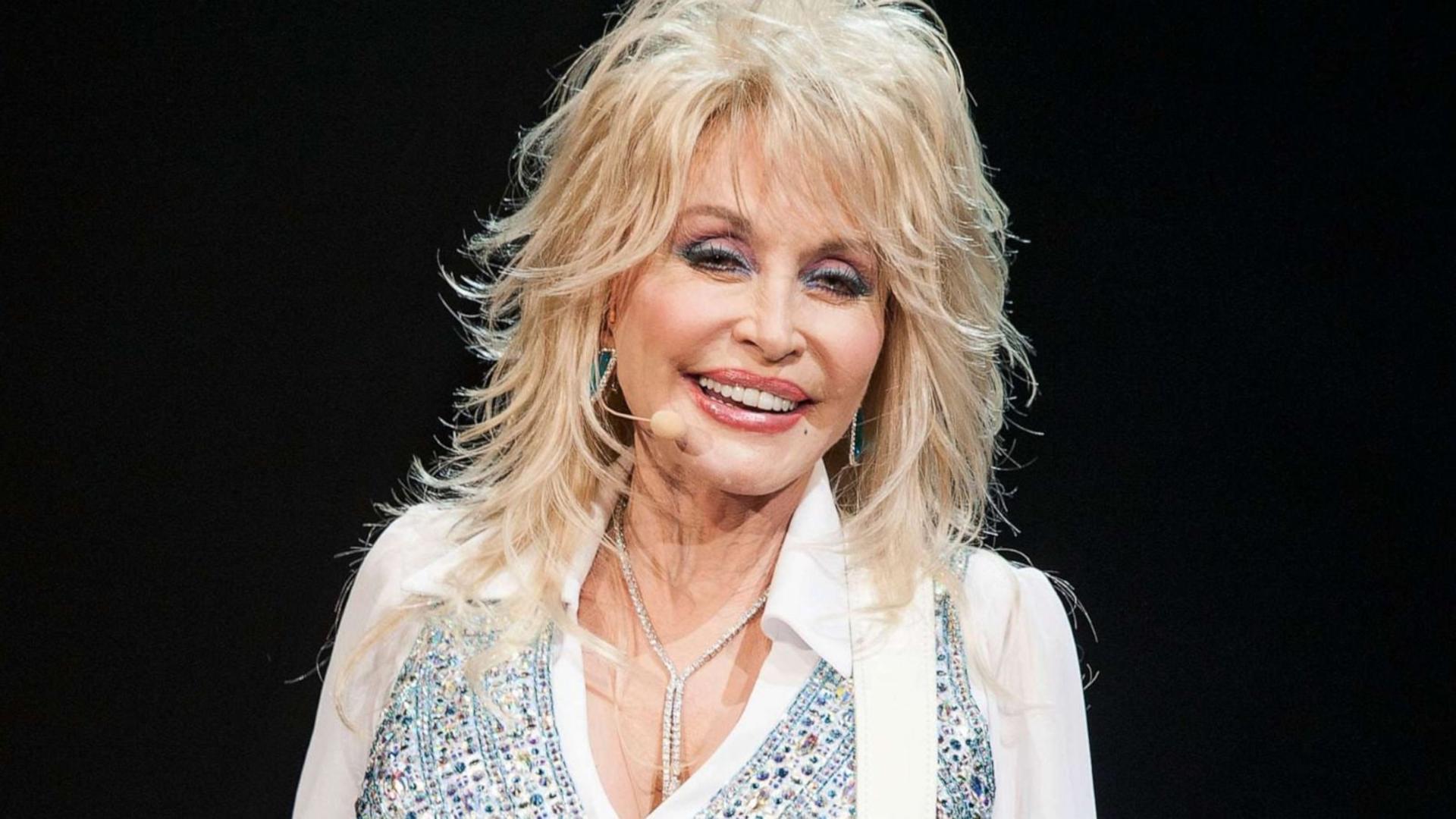 دالی پارتون (Dolly Parton) خواننده مشهور با موهای بلوند در اجرا
