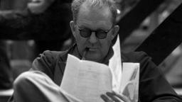 جان فورد (John Ford) با عینک در حال مطالعه برگه‌های کاغذ