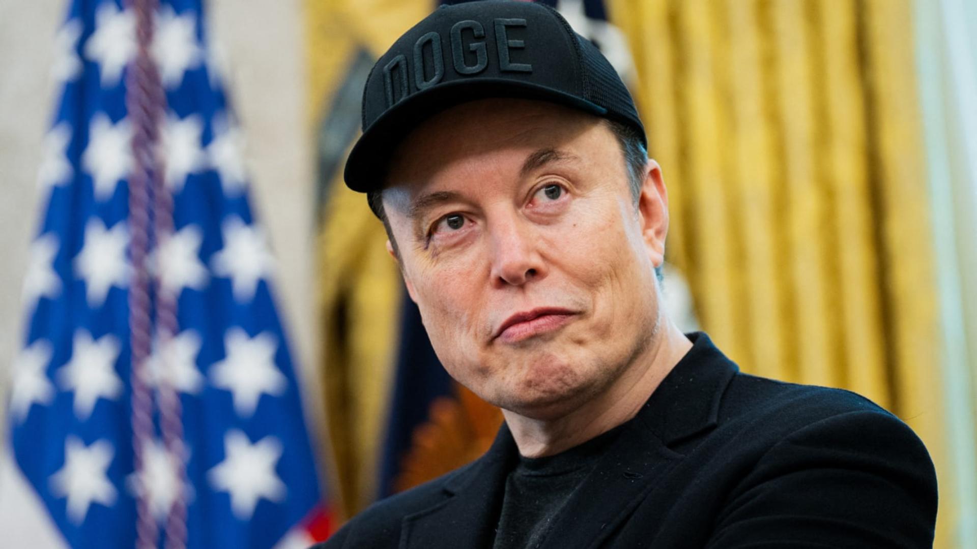 ایلان ماسک (Elon Musk) با کلاه سیاه که روی آن نوشته شده DOGE است
