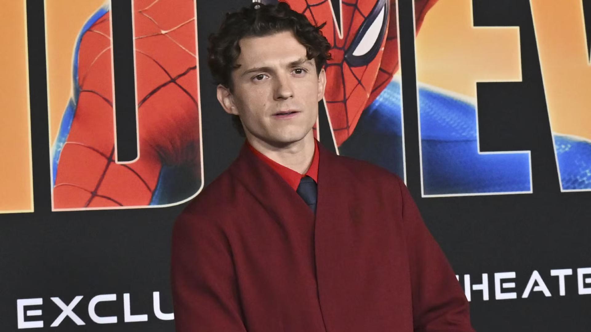 تام هالند (Tom Holland) در مقابل پوستر فیلم مرد عنکبوتی