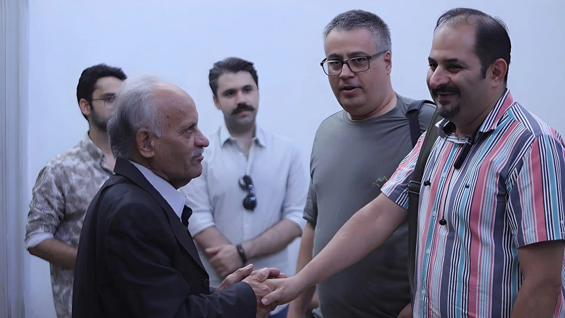 دست دادن مرد سالخورده با مرد جوان‌تر در مراسم مستند کهنه رفیق