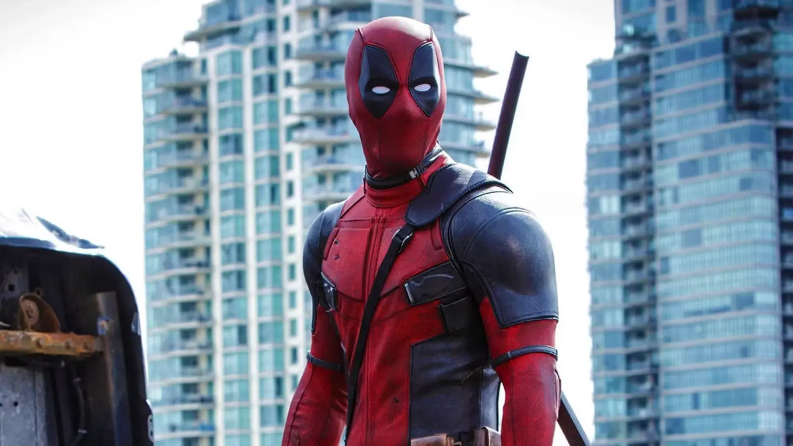شخصیت ددپول (Deadpool) با لباس قرمز و مشکی در مقابل ساختمان‌های بلند شهری