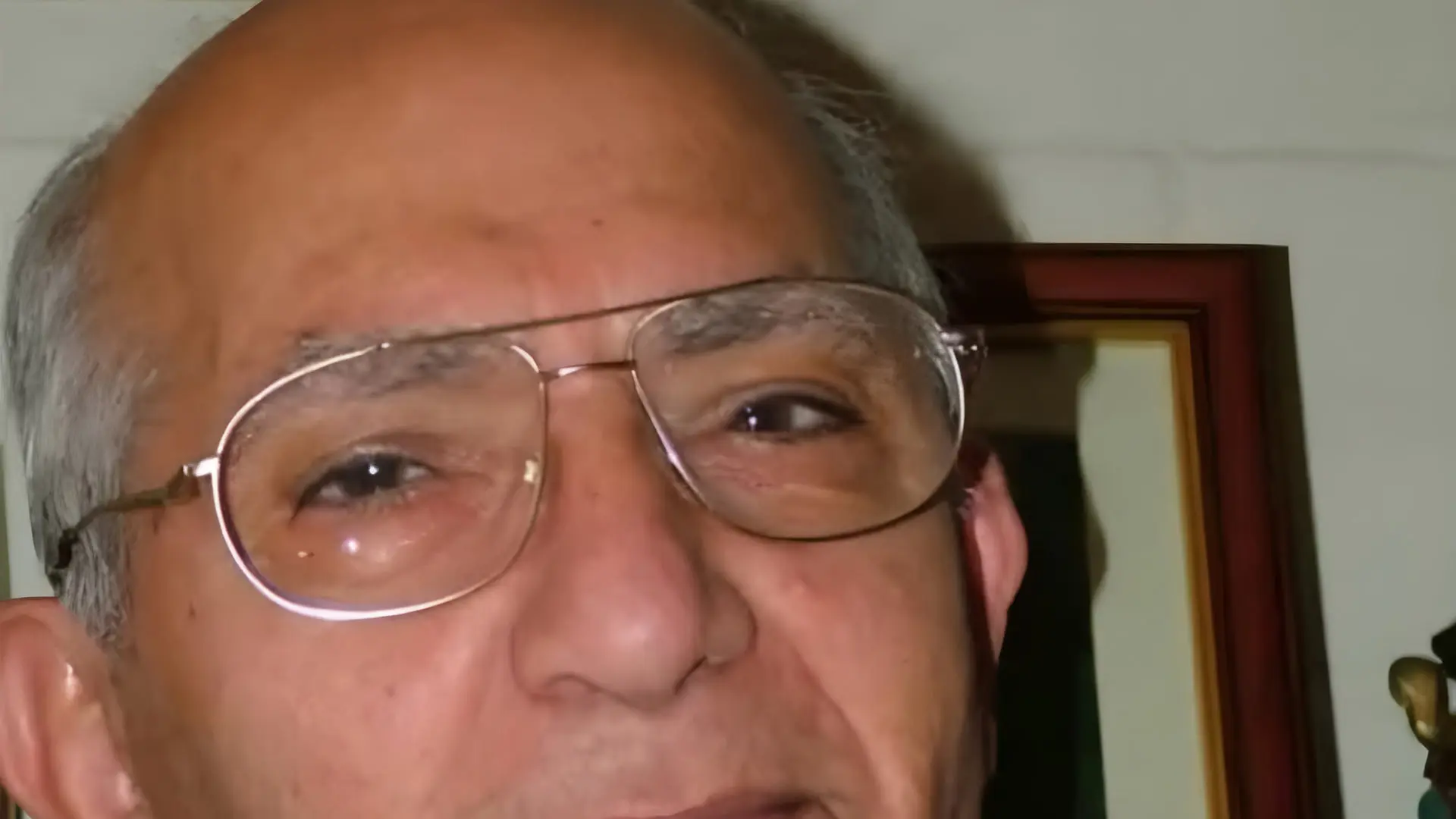 مرد مسنی با عینک طبی که به دوربین نگاه می‌کند