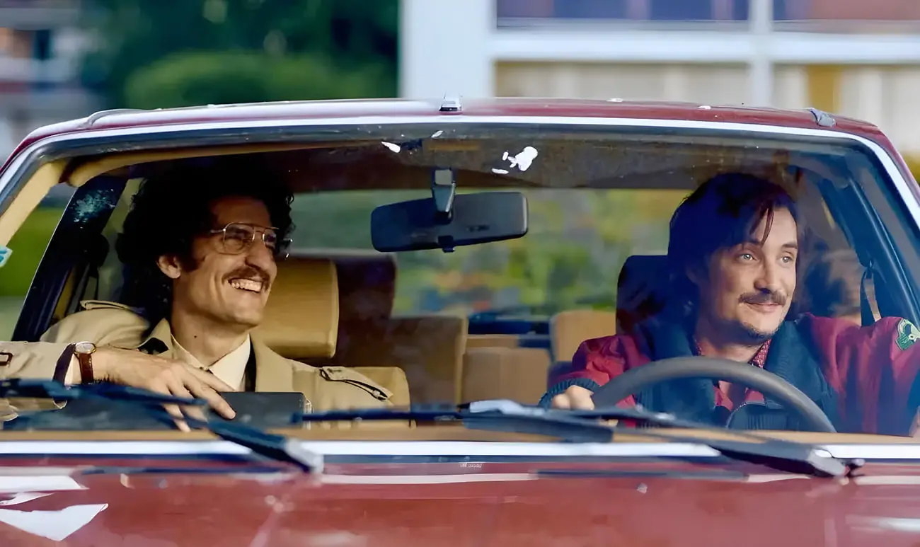 دو مرد در حال رانندگی با خودروی قدیمی در یک فیلم فرانسوی