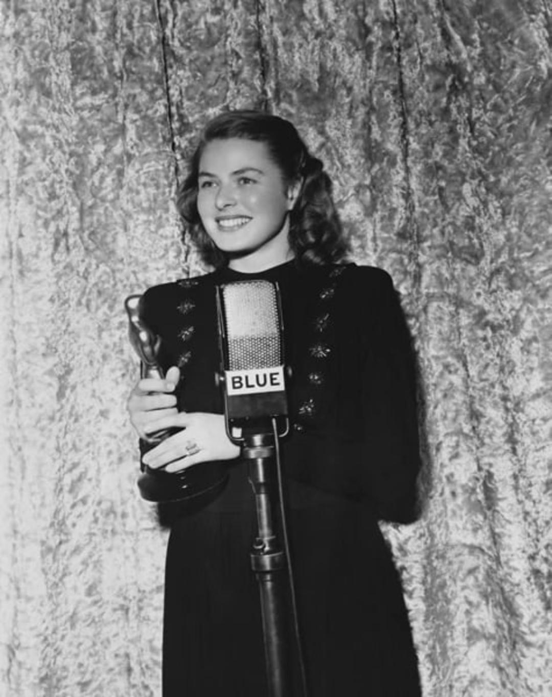 اینگرید برگمن (Ingrid Bergman) در حال نگه داشتن تندیس اسکار در مقابل میکروفون
