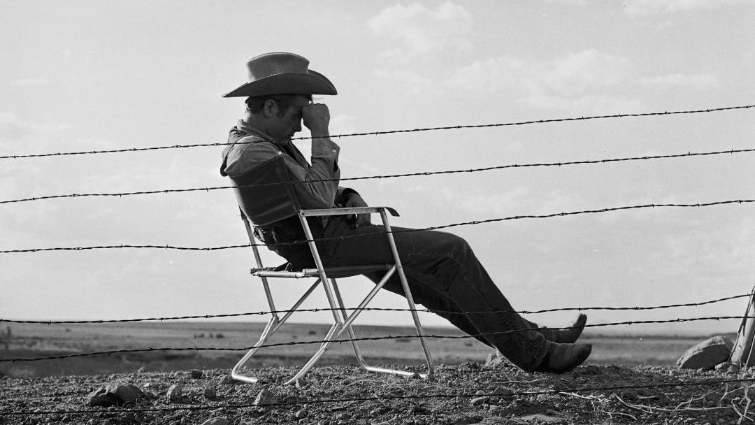 جیمز دین (James Dean) با کلاه گاوی روی صندلی نشسته است
