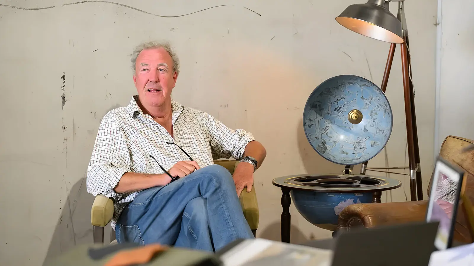 جرمی کلارکسون (Jeremy Clarkson) در محیطی با دکوراسیون کلاسیک و کره زمین