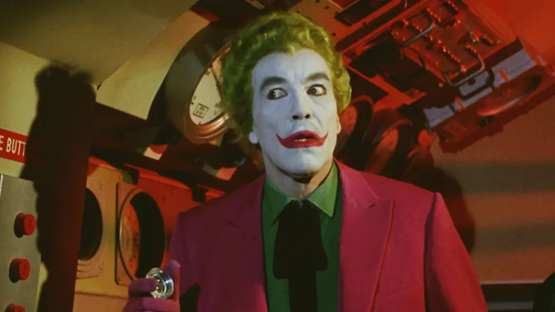 جوکر (Joker) با آرایش کلاسیک و کت صورتی در محیطی تاریک