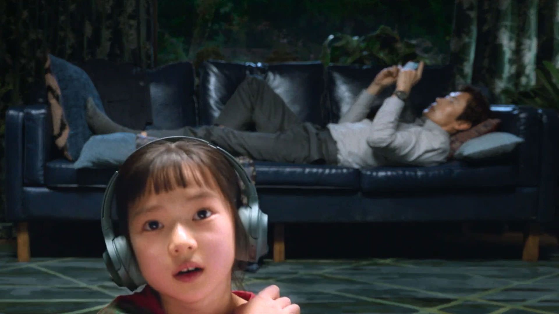 دخترکی در پیش‌زمینه‌ی نما نشسته است در حالی که لی بیونگ هون موبایل به دست در پس‌زمینه‌ی نما دراز کشیده است در نمایی از فیلم چاره‌ای نیست به کارگردانی پارک چان ووک