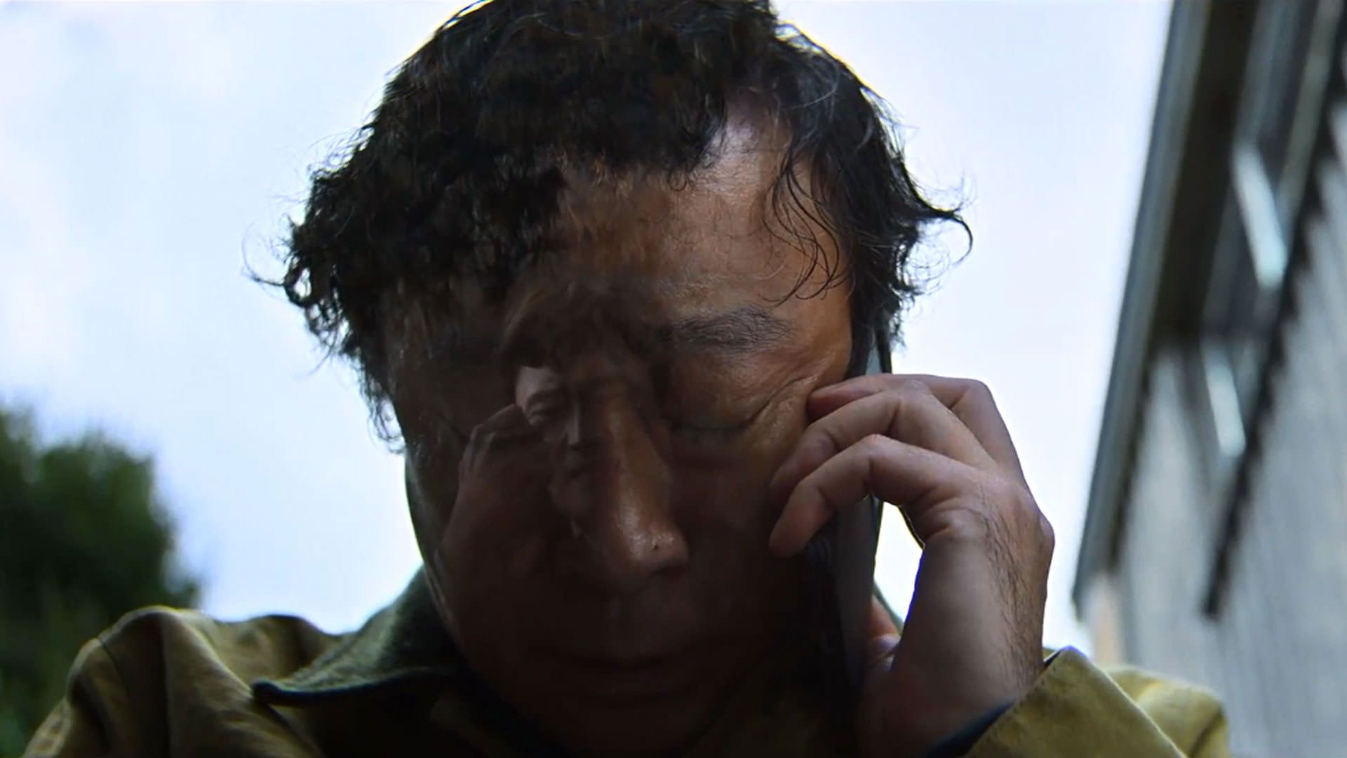 لی سونگ مین گریان با تلفن حرف می‌زند در نمایی از فیلم چاره‌ای نیست به کارگردانی پارک چان ووک