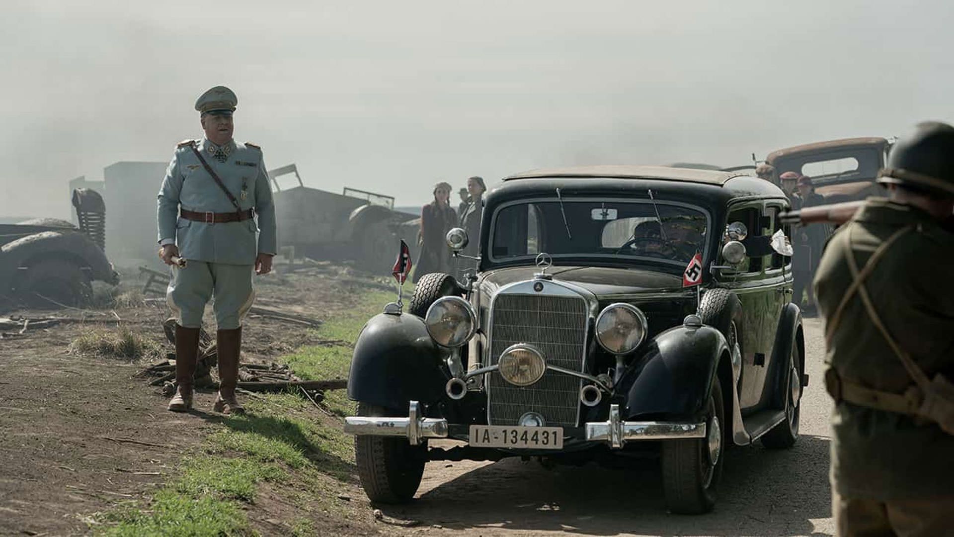 راسل کرو با لباس یک فرمانده نظامی نازی کنار خودرویی قدیمی ایستاده است در نمایی از فیلم نورنبرگ جیمز وندربیلت
