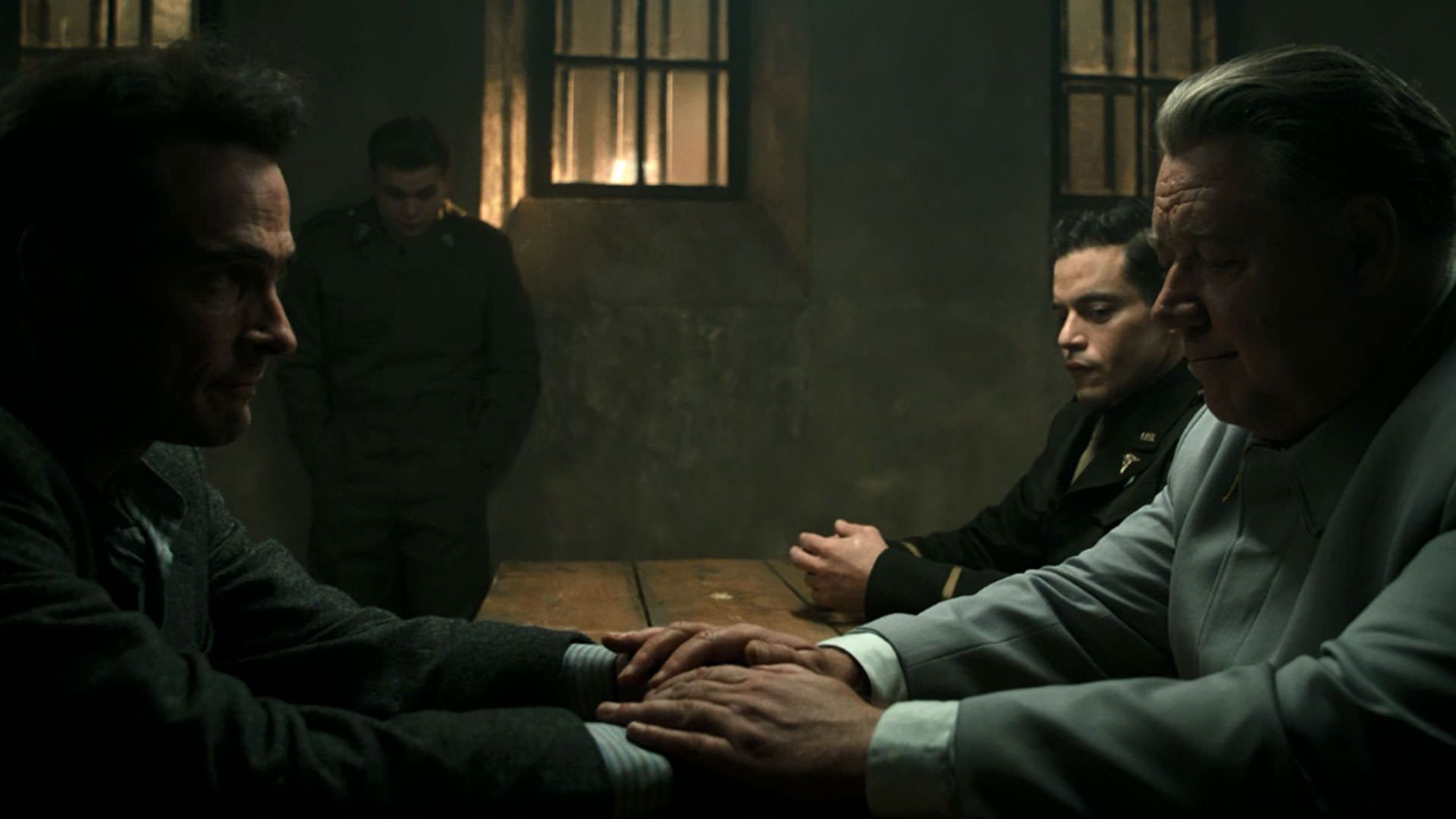 راسل کرو دستان آندریاس پیچمن را گرفته است در حالی که رامی مالک در کنارش نشسته در فیلم نورنبرگ جیمز وندربیلت