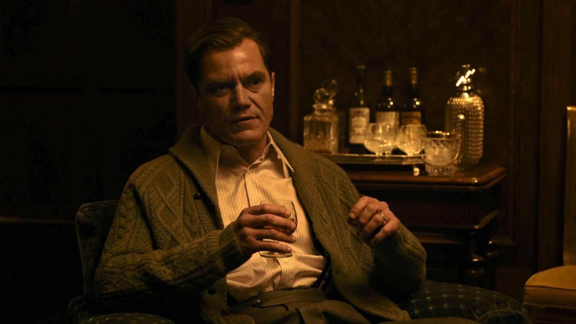 مایکل شانون با لیوان نوشیدنی در دست نشسته است و صحبت می‌کند در فیلم نورنبرگ جیمز وندربیلت