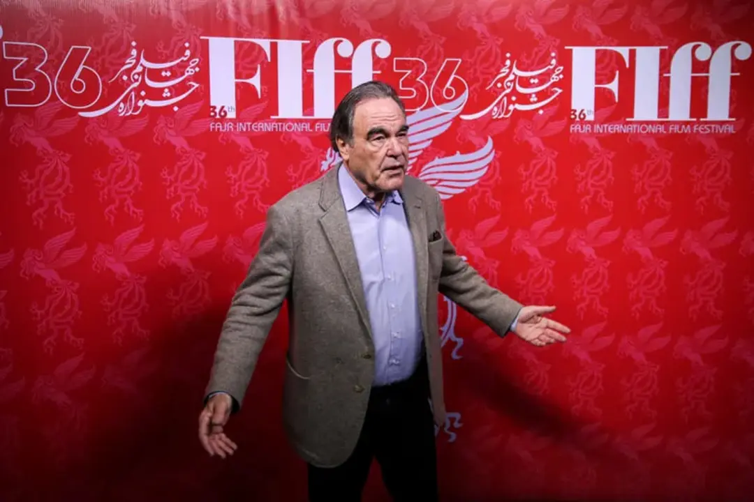 اولیور استون (Oliver Stone) در مقابل بنر سی و ششمین دوره جشنواره فیلم فجر