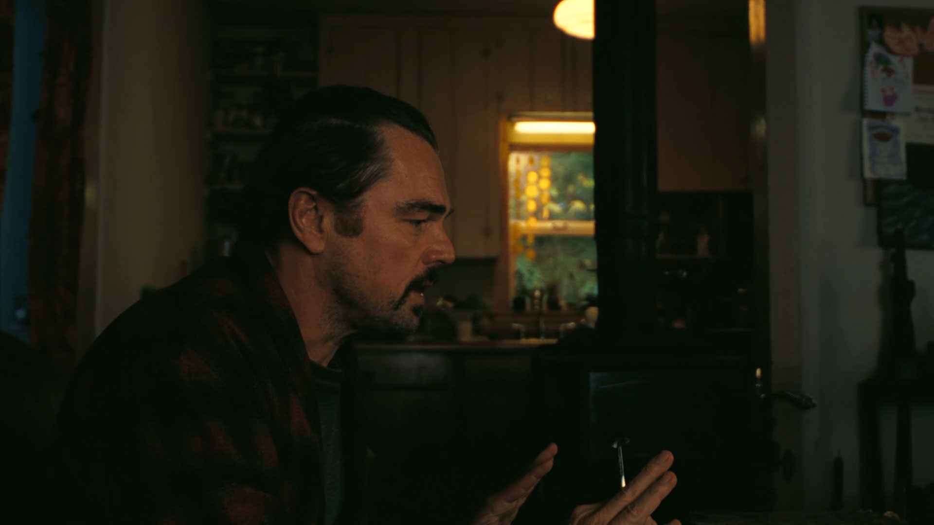 لئوناردو دیکاپریو به تنهایی نشسته است در نمایی از فیلم نبرد پشت نبرد پل توماس اندرسون