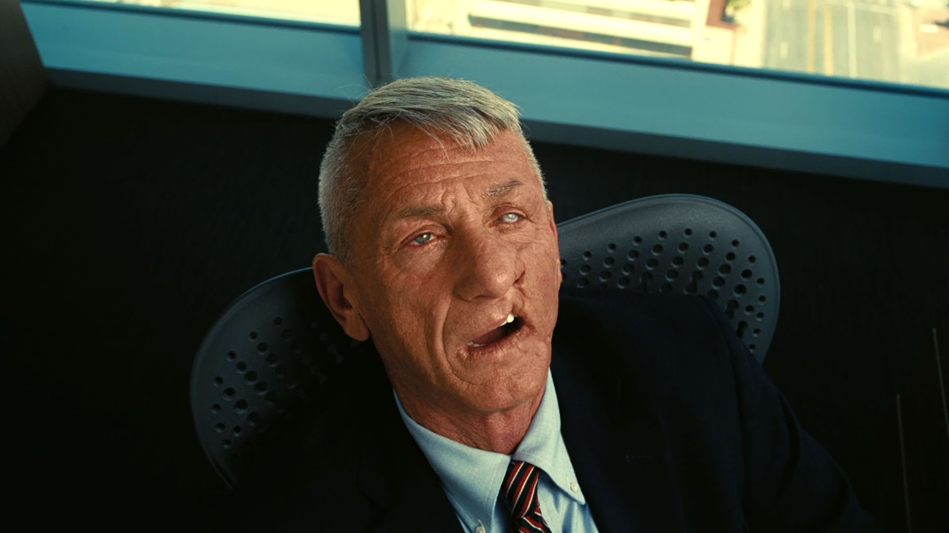 شان پن با صورتی سوخته و دهانی باز روی یک صندلی جان داده است در نمایی از فیلم نبرد پشت نبرد پل توماس اندرسون