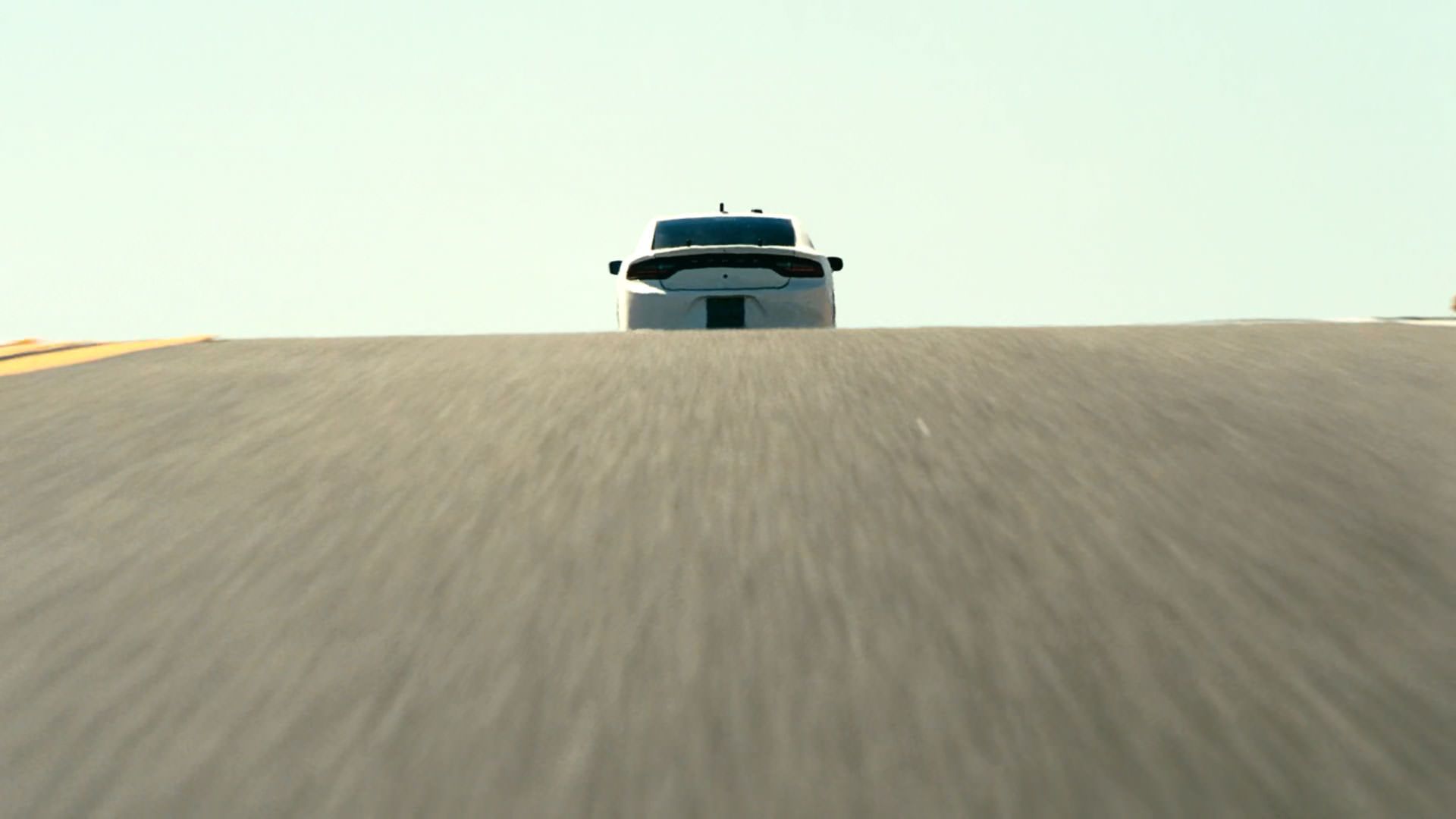 یک ماشین با سرعت به ماشینی دیگر داخل جاده نزدیک می‌شود در نمایی از فیلم نبرد پشت نبرد پل توماس اندرسون