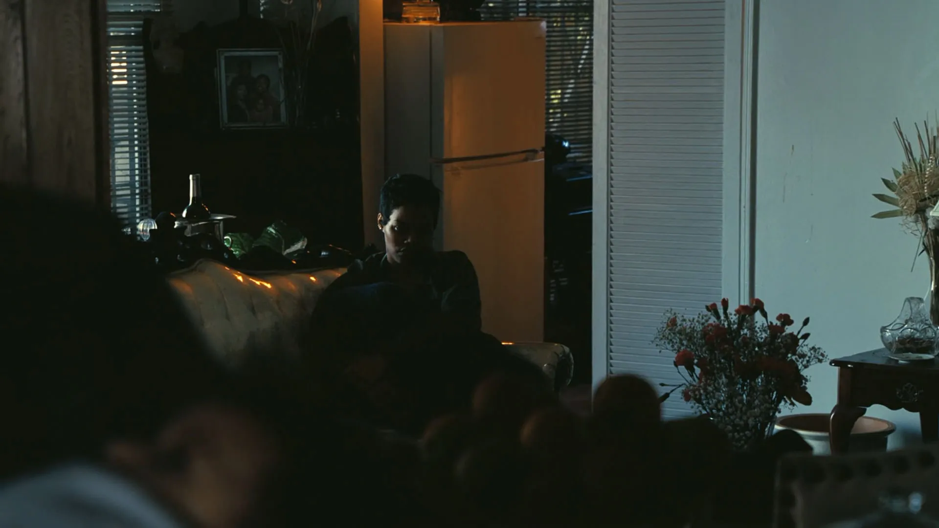 تیانا تیلور به‌تنهایی در عمق نما نشسته است در نمایی از فیلم نبرد پشت نبرد پل توماس اندرسون