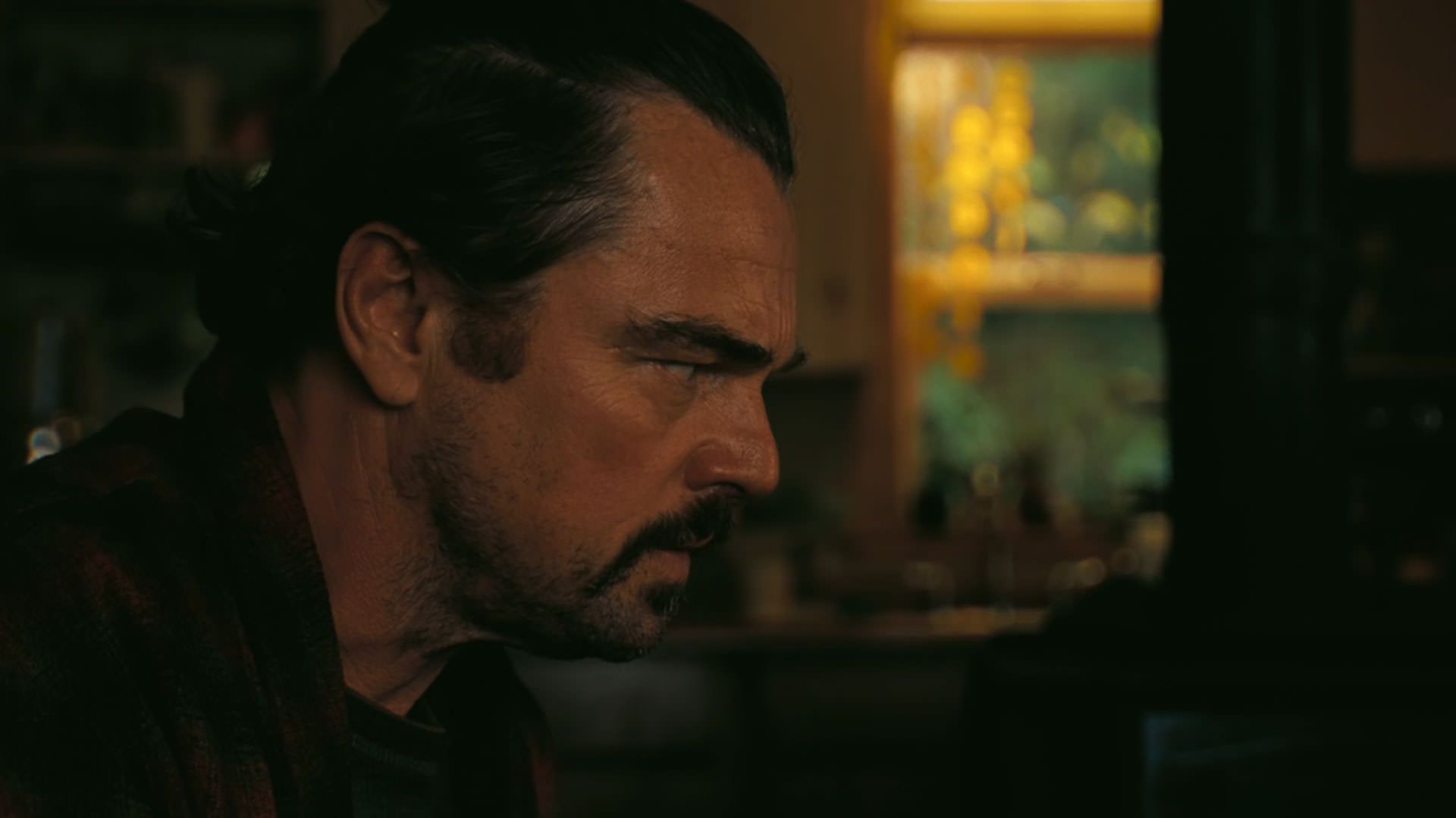 لئوناردو دیکاپریو نشسته داخل خانه در نمایی از فیلم نبرد پشت نبرد پل توماس اندرسون
