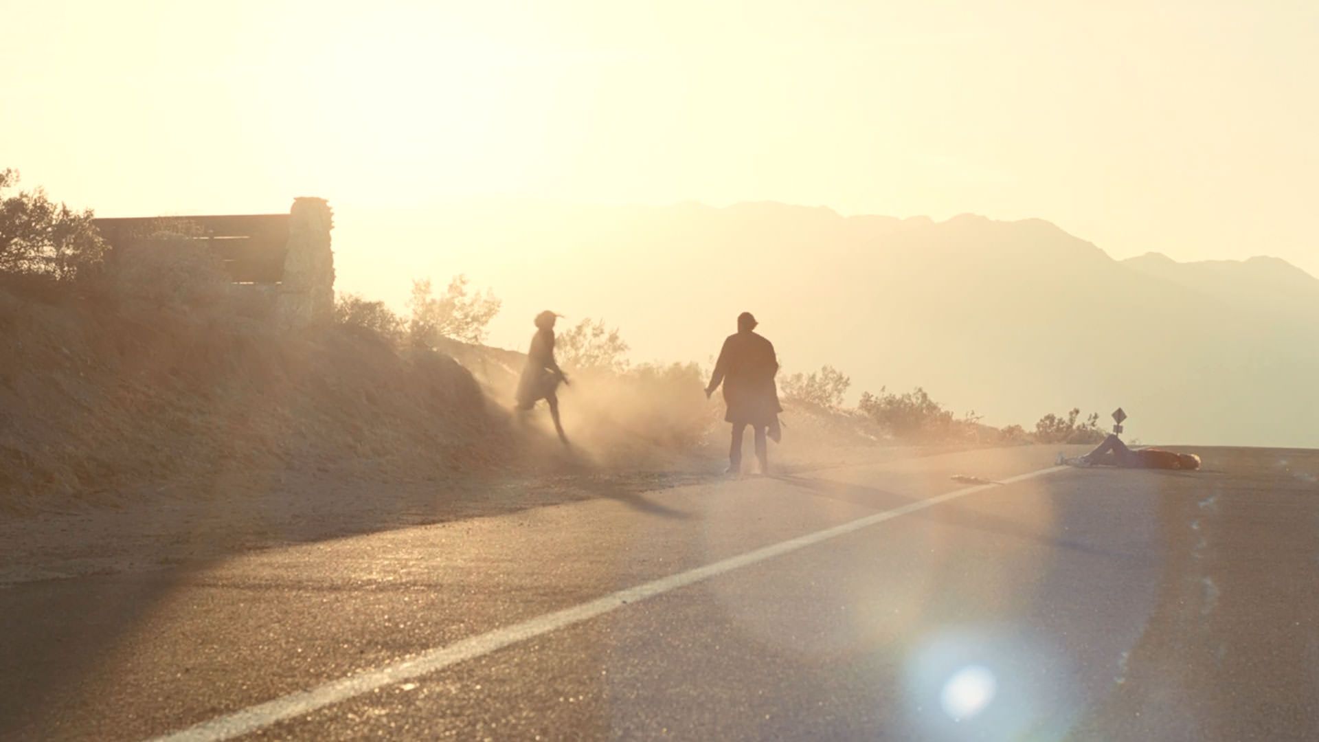 یک مرد و زن زیر نور آفتاب وسط یک جاده به سمت هم می‌روند در نمایی از فیلم نبرد پشت نبرد پل توماس اندرسون
