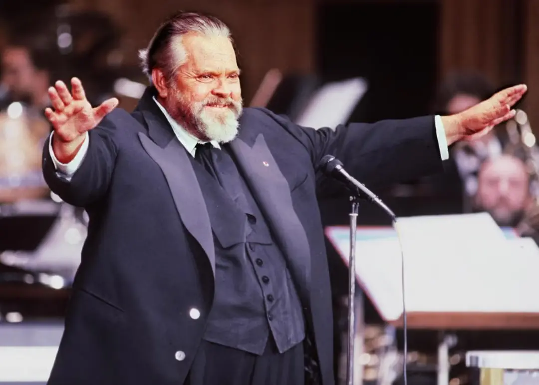 اورسن ولز (Orson Welles) با لباس رسمی در حال رهبری ارکستر موسیقی