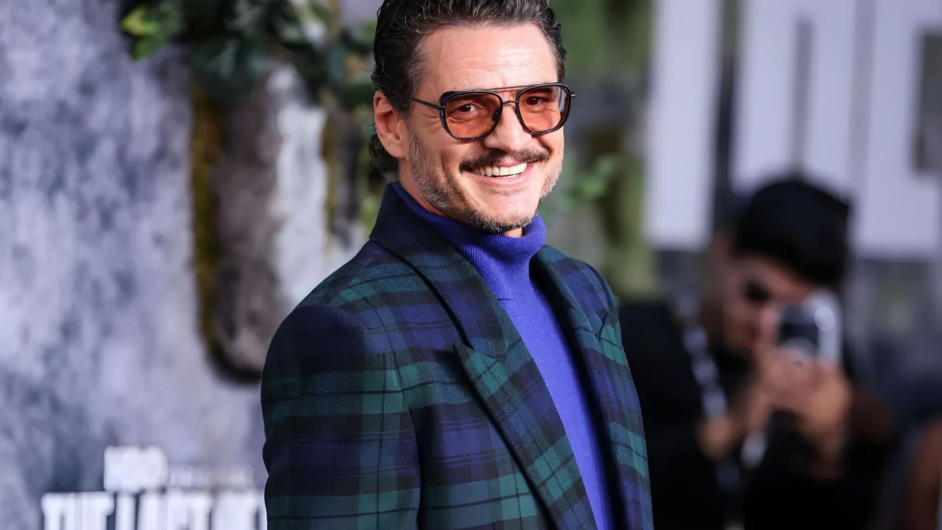 پدرو پاسکال (Pedro Pascal) با عینک آفتابی و کت چهارخانه در حال لبخند زدن