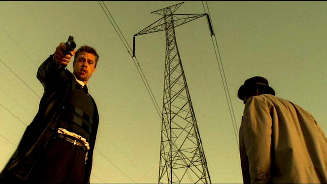 برد پیت (Brad Pitt) در حال نشانه رفتن با تفنگ در مقابل دکل برق