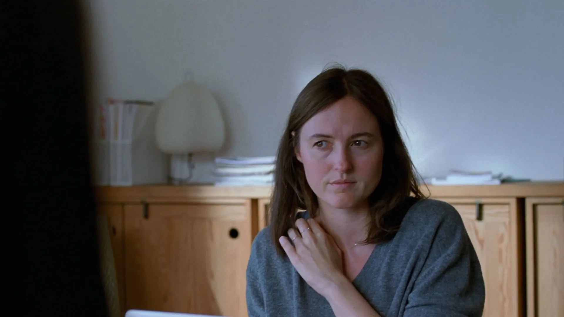 رناته رینسوه غمگین پشت میز نشسته است در فیلم ارزش عاطفی یواکیم تریه