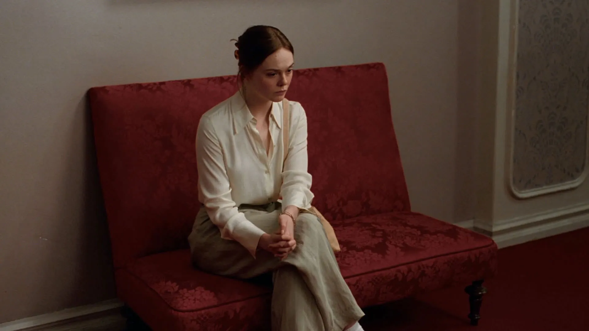 ال فنینگ نشسته روی صندلی قرمز در فیلم ارزش عاطفی یواکیم تریه