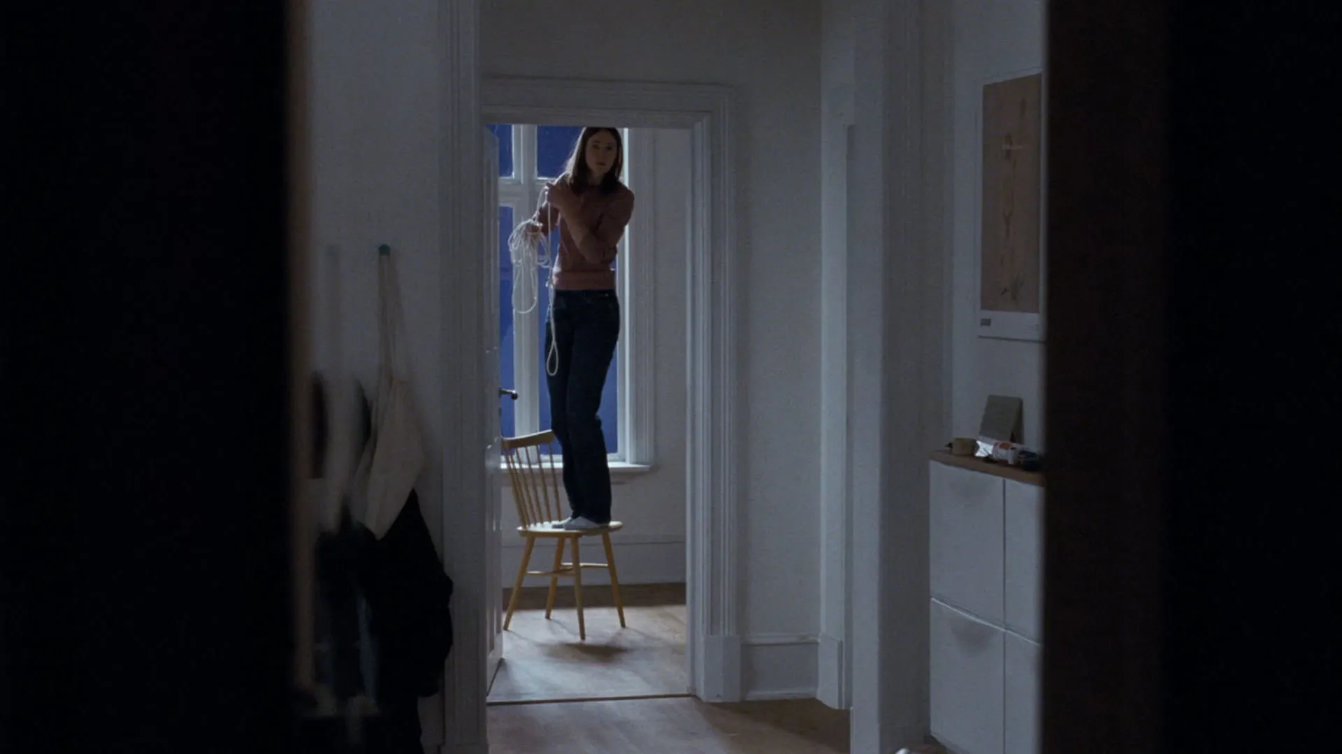 رناته رینسوه روی صندلی ایستاده است و طنابی را از سقف آویزان می‌کند در فیلم ارزش عاطفی یواکیم تریه