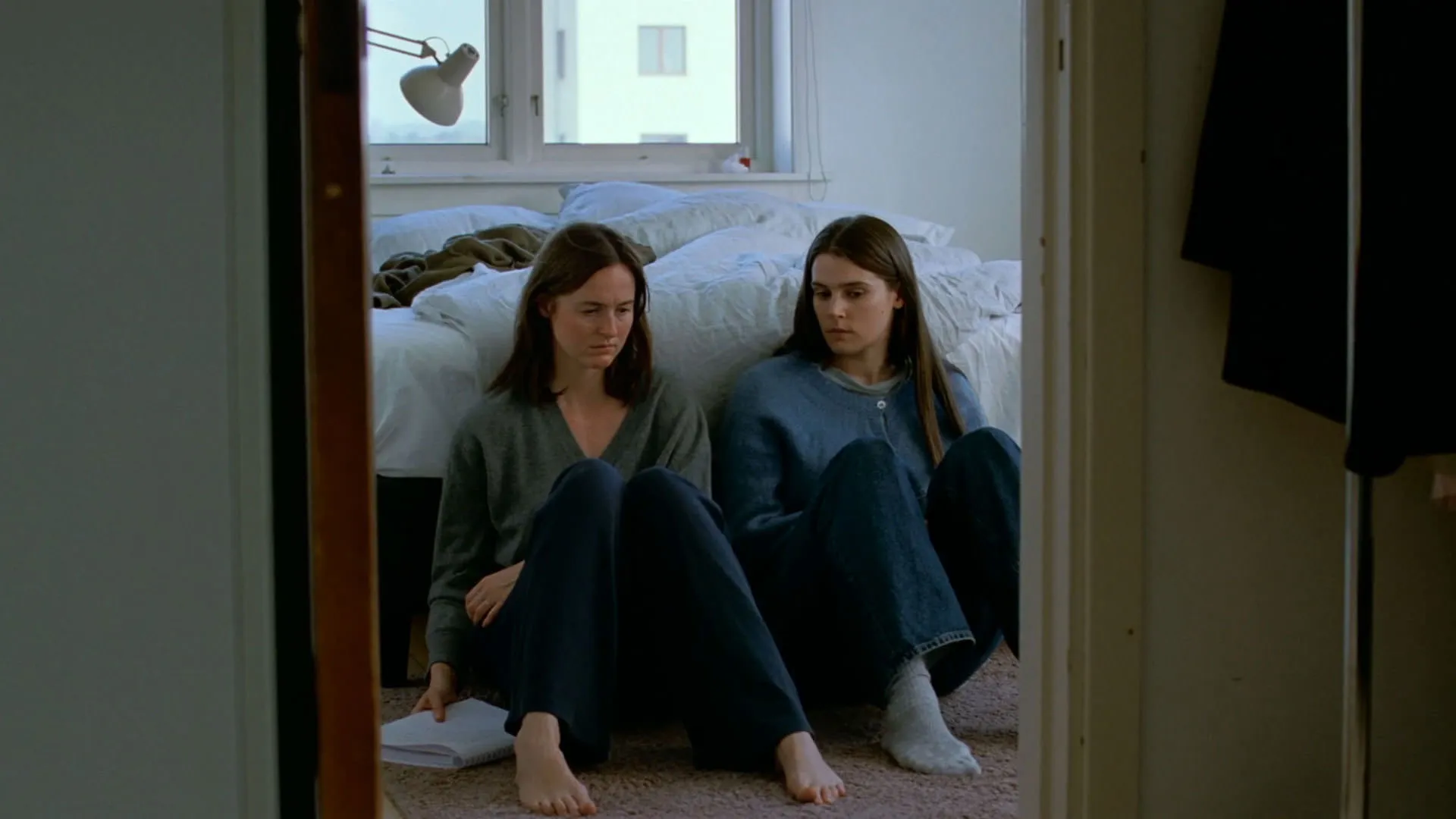 رناته رینسوه پشت به تخت خواب و در کنار اینگا ایبسدوتر لیلیاس نشسته است در فیلم ارزش عاطفی یواکیم تریه