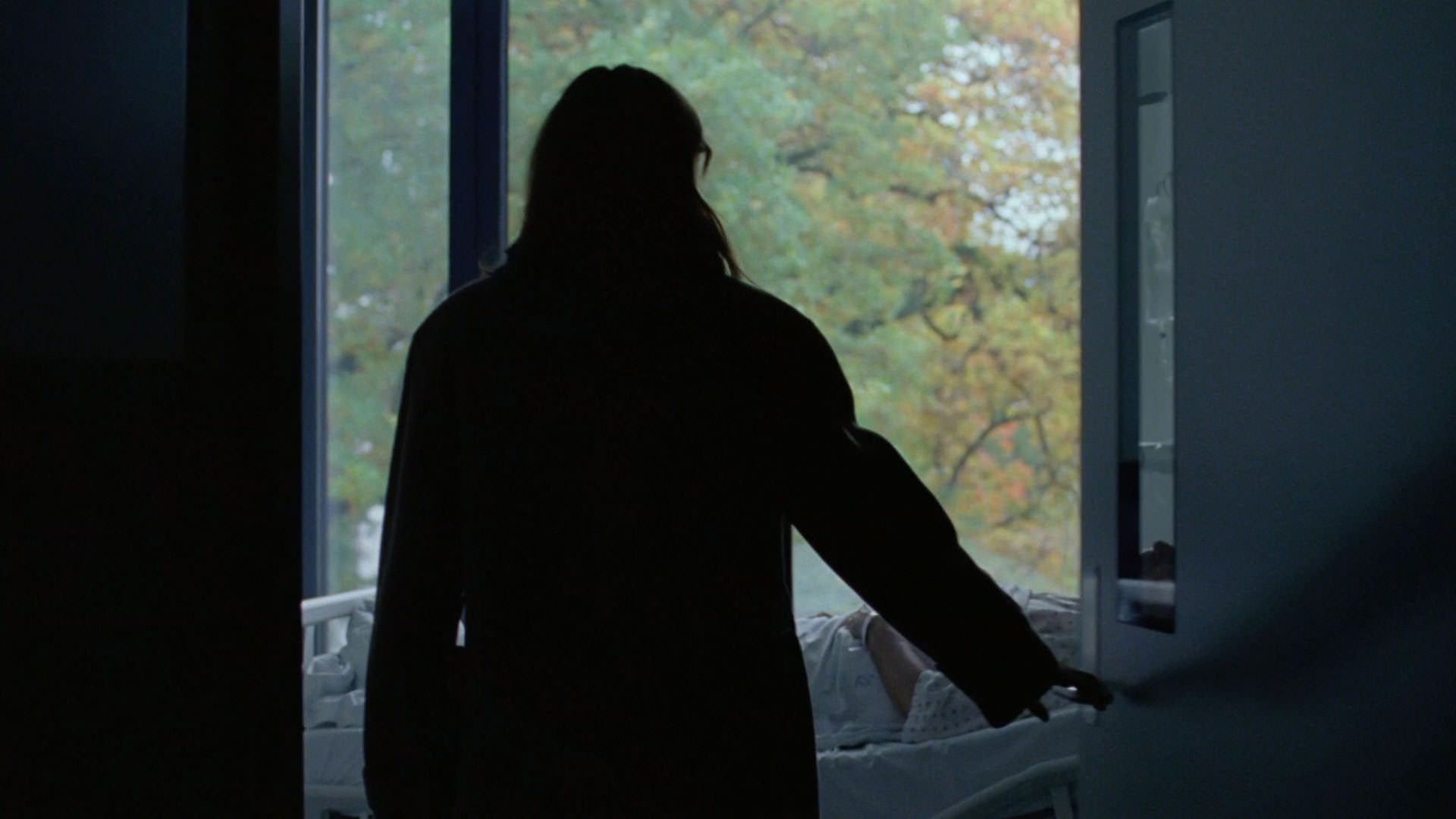 رناته رینسوه پشت به دوربین در اتاق بیمارستانی را باز میکند در فیلم ارزش عاطفی یواکیم تریه