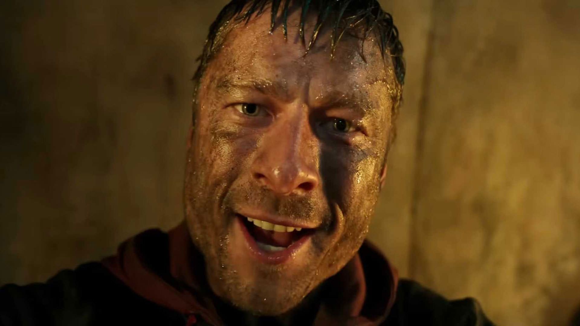 گلن پاول با چهره‌ای کثیف به دوربین نگاه می‌کند در نمایی از فیلم مرد فراری ادگار رایت