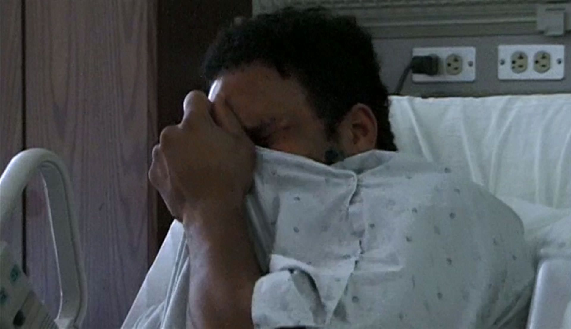 مارک کر در حال گریه کردن روی تخت بیمارستان صورت‌اش را پوشانده است در نمایی از مستند ماشین کوبنده به کارگردانی جان هایمز