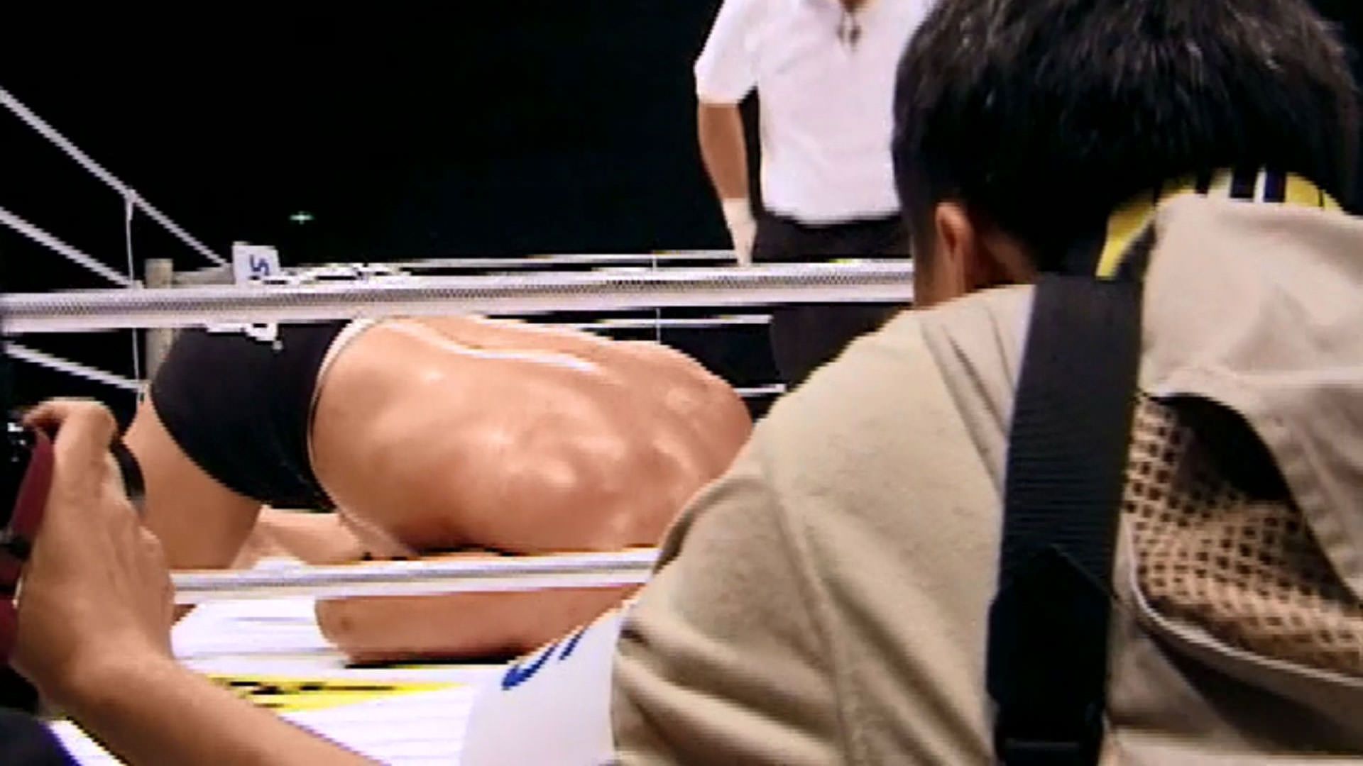 در کنار عکاسان می‌بینیم که مارک کر داخل رینگ مبارزه ناک اوت شده است در نمایی از مستند ماشین کوبنده به کارگردانی جان هایمز