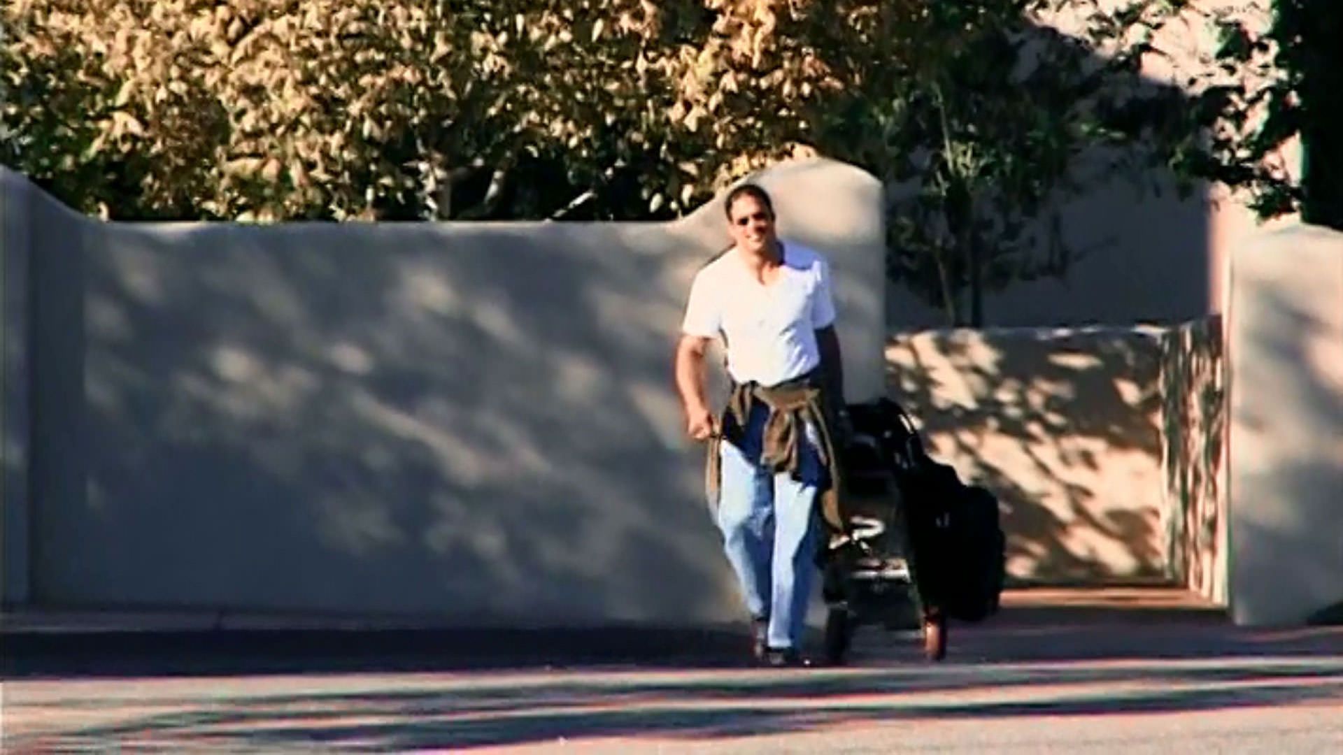 مارک کر با لباسی سفید و چمدانی در دست در حال خروج از کمپ بازپروری در نمایی از مستند ماشین کوبنده به کارگردانی جان هایمز