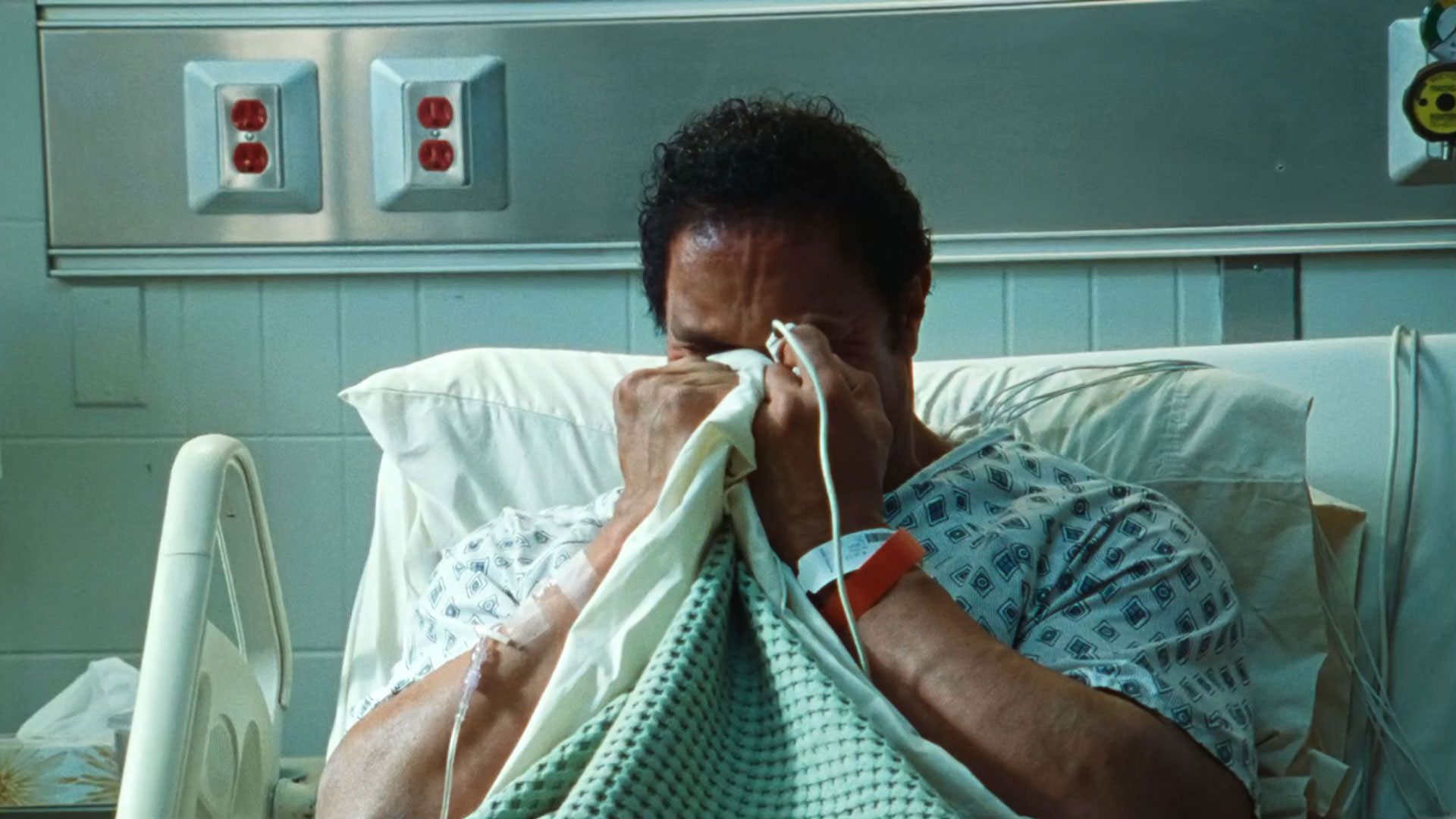 دواین جانسون راک روی تخت بیمارستان گریه می‌کند و صورت‌اش را می‌پوشاند در نمایی از فیلم ماشین کوبنده به کارگردانی بنی سفدی